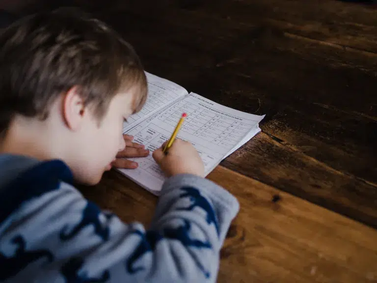 kid solving maths problem on a workbook