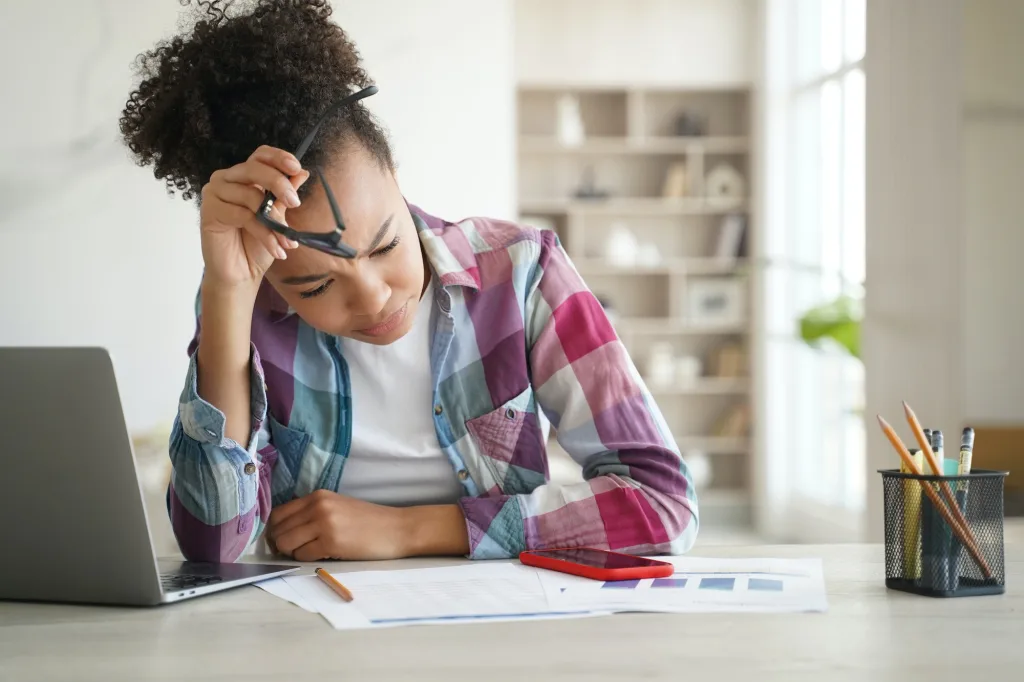 Mixed race school student girl studying with laptop at desk, preparing for eqao test. Academic stress